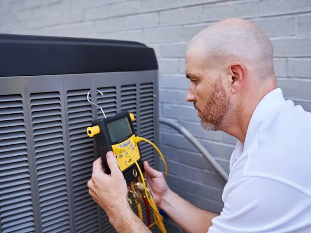 HVAC technician testing an outdoor unit with an electrical diagnostic meter