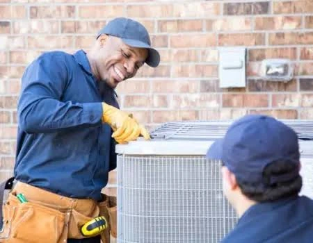 Two service technicians inspecting residential outdoor HVAC equipment