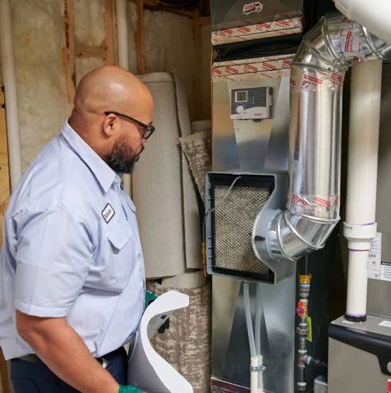 Heating technician inspecting an indoor furnace and its duct connections